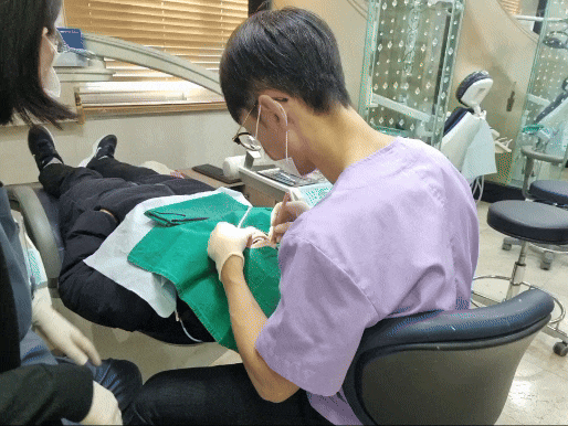 치과 진료실에서 환자가 누워있고 치과의사가 환자의 치아를 치료하는 모습